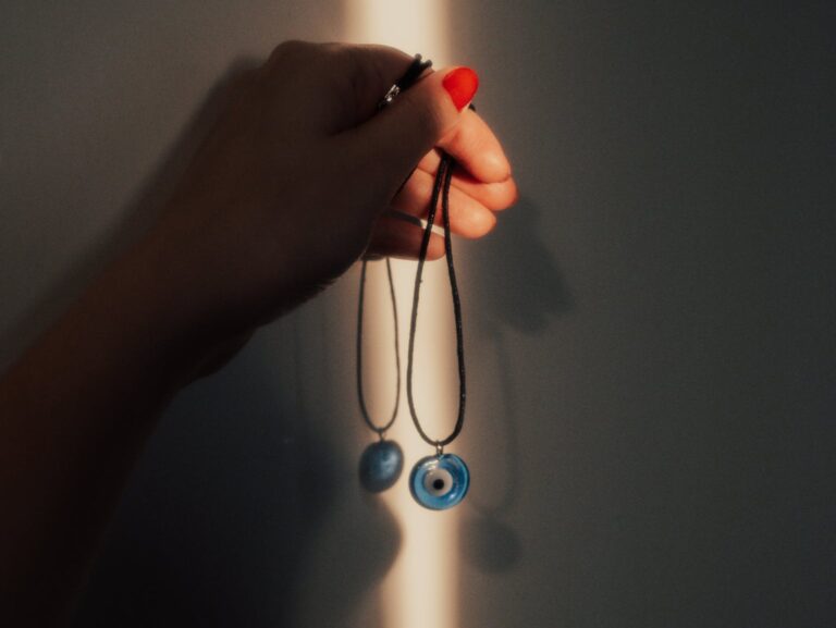 Hand Holding a Necklace with Evil Eye Pendant 